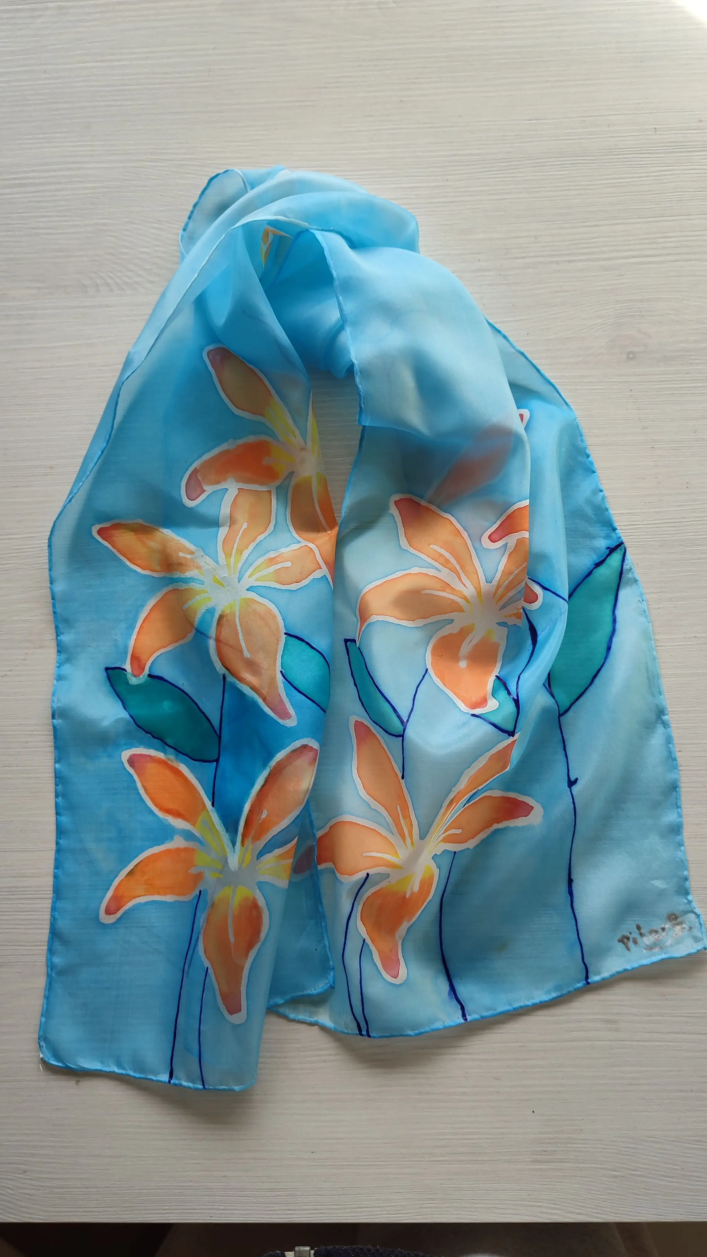 Fular de seda pintado a mano con azucenas naranjas sobre fondo azul – Accesorio elegante y único